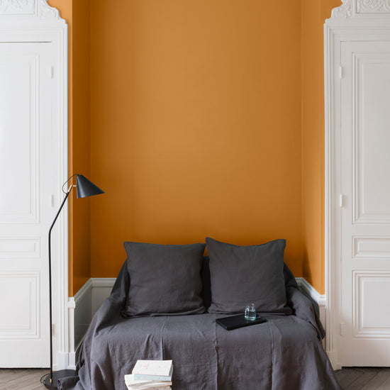 Salon aux murs Orangette, Velours de Peinture Libéron, avec canapé gris, portes blanches et parquet clair.