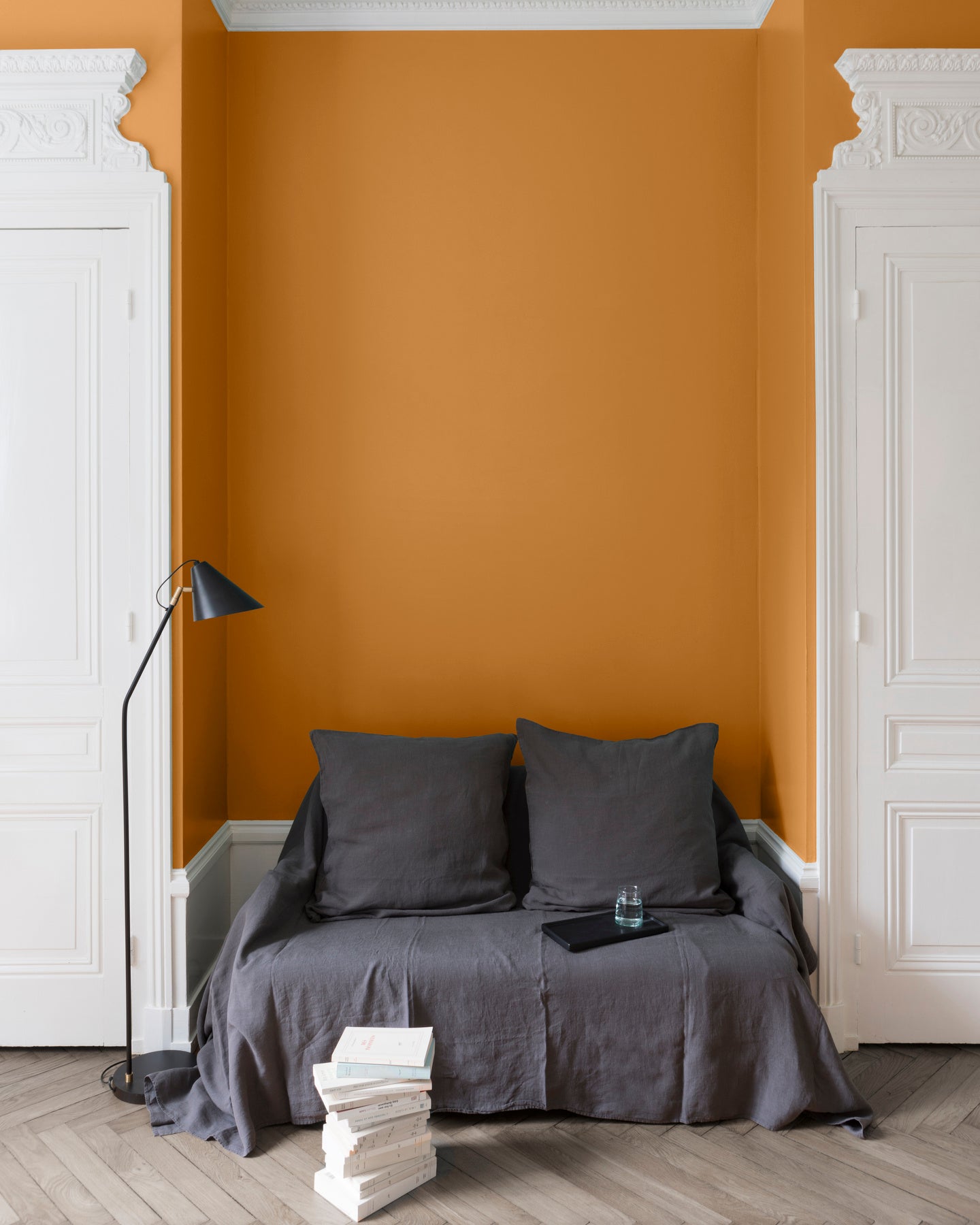 Salon aux murs Orangette, Velours de Peinture Libéron, avec canapé gris, portes blanches et parquet clair.