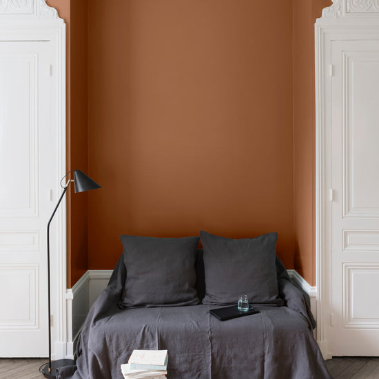 Salon aux murs oranges, peinture Velours de Peinture Pain d'Épices Libéron avec portes blanches et textiles gris.