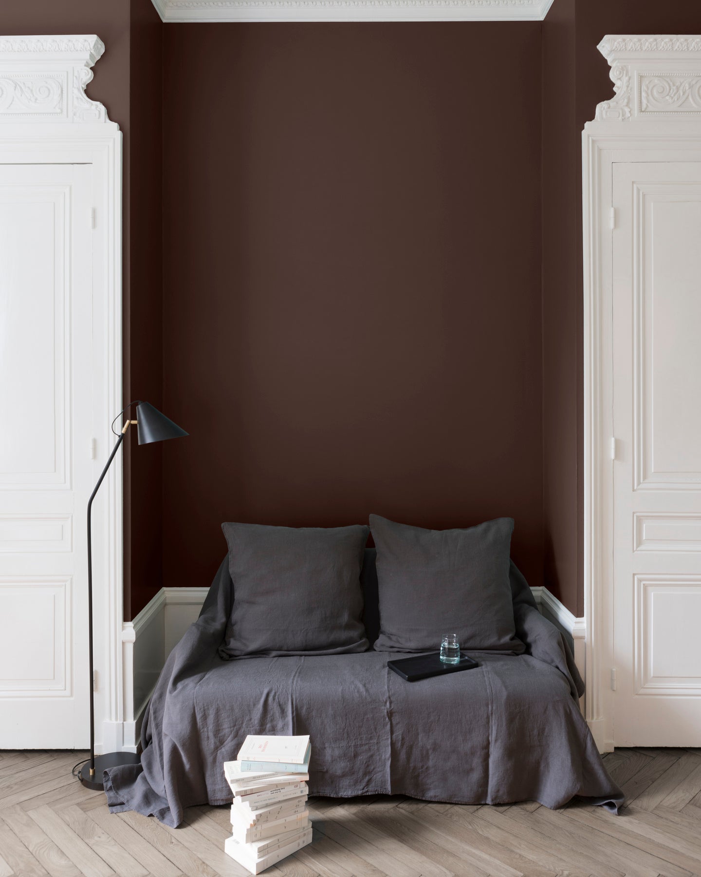 Salon aux murs bruns, peinture Velours de Peinture Palissandre Libéron avec portes blanches et textiles gris.