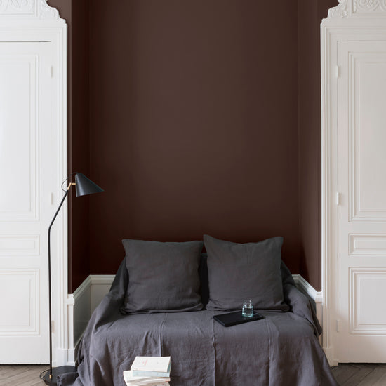 Salon aux murs Palissandre, Velours de Peinture Libéron, avec canapé gris, portes blanches et parquet clair.