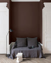 Salon aux murs Palissandre, Velours de Peinture Libéron, avec canapé gris, portes blanches et parquet clair.