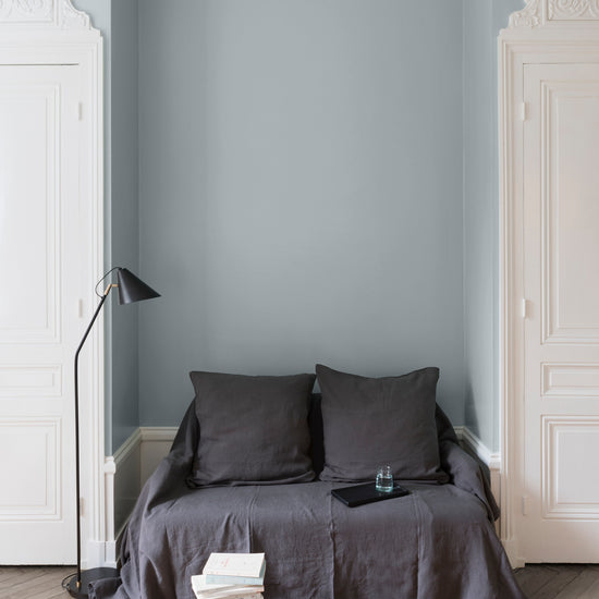 Salon aux murs bleus, peinture Velours de Peinture Petit Bleu Libéron avec portes blanches et textiles gris.
