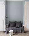 Salon aux murs Petit Bleu, Velours de Peinture Libéron, avec canapé gris, portes blanches et parquet clair.