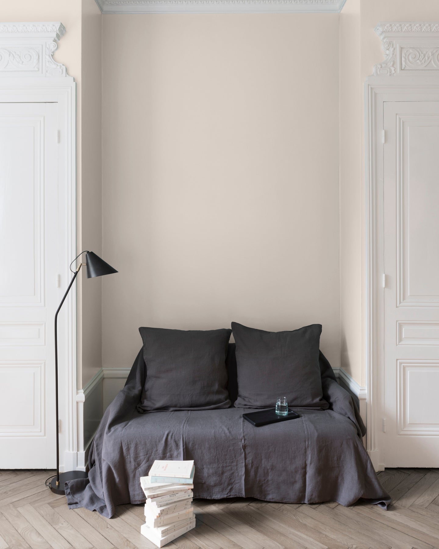 Salon aux murs Poudre de Riz, Velours de Peinture Libéron, avec canapé gris, portes blanches et parquet clair.