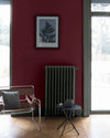 Salon lumineux avec murs rouges, peinture Velours de Peinture Rouge Cardinal Libéron, avec mobilier gris, table basse et chaise marron 