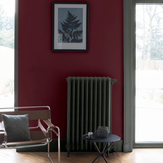 Salon lumineux avec murs rouges, peinture Velours de Peinture Rouge Cardinal Libéron, avec mobilier gris, table basse et chaise marron 
