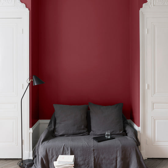 Salon aux murs rouges, peinture Velours de Peinture Rouge Odéon Libéron avec portes blanches et textiles gris.