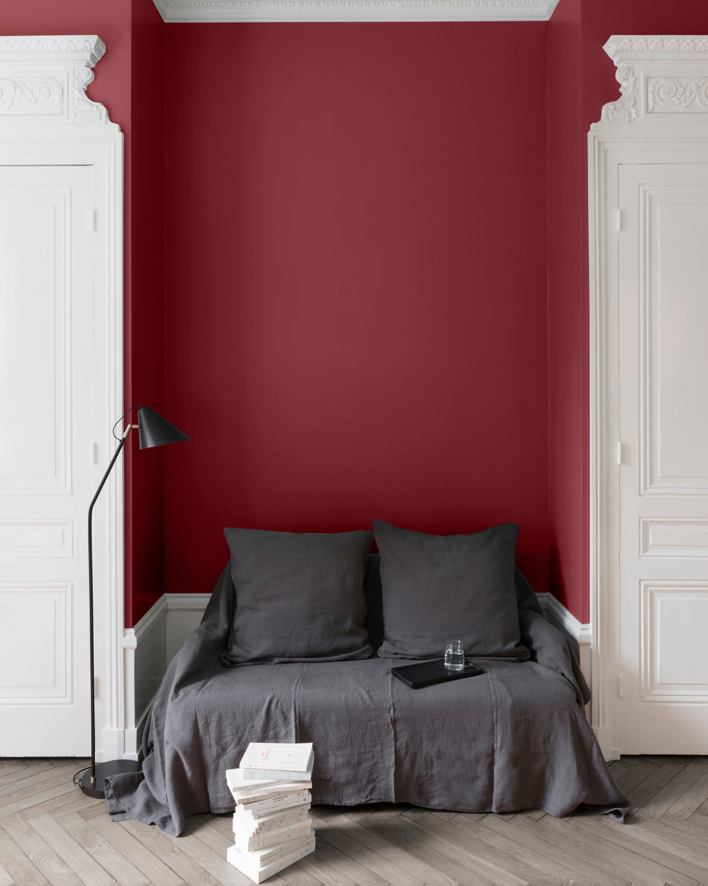 Salon aux murs rouges, peinture Velours de Peinture Rouge Odéon Libéron avec portes blanches et textiles gris.