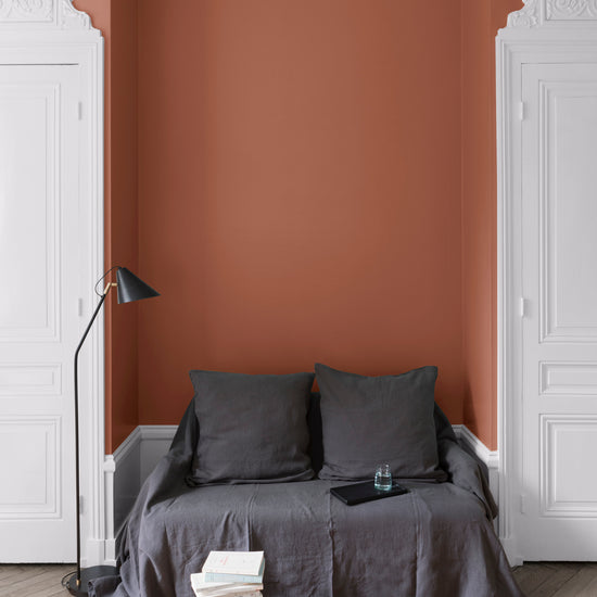 Salon aux murs Roux du Goupil, Velours de Peinture Libéron, avec canapé gris, portes blanches et parquet clair.