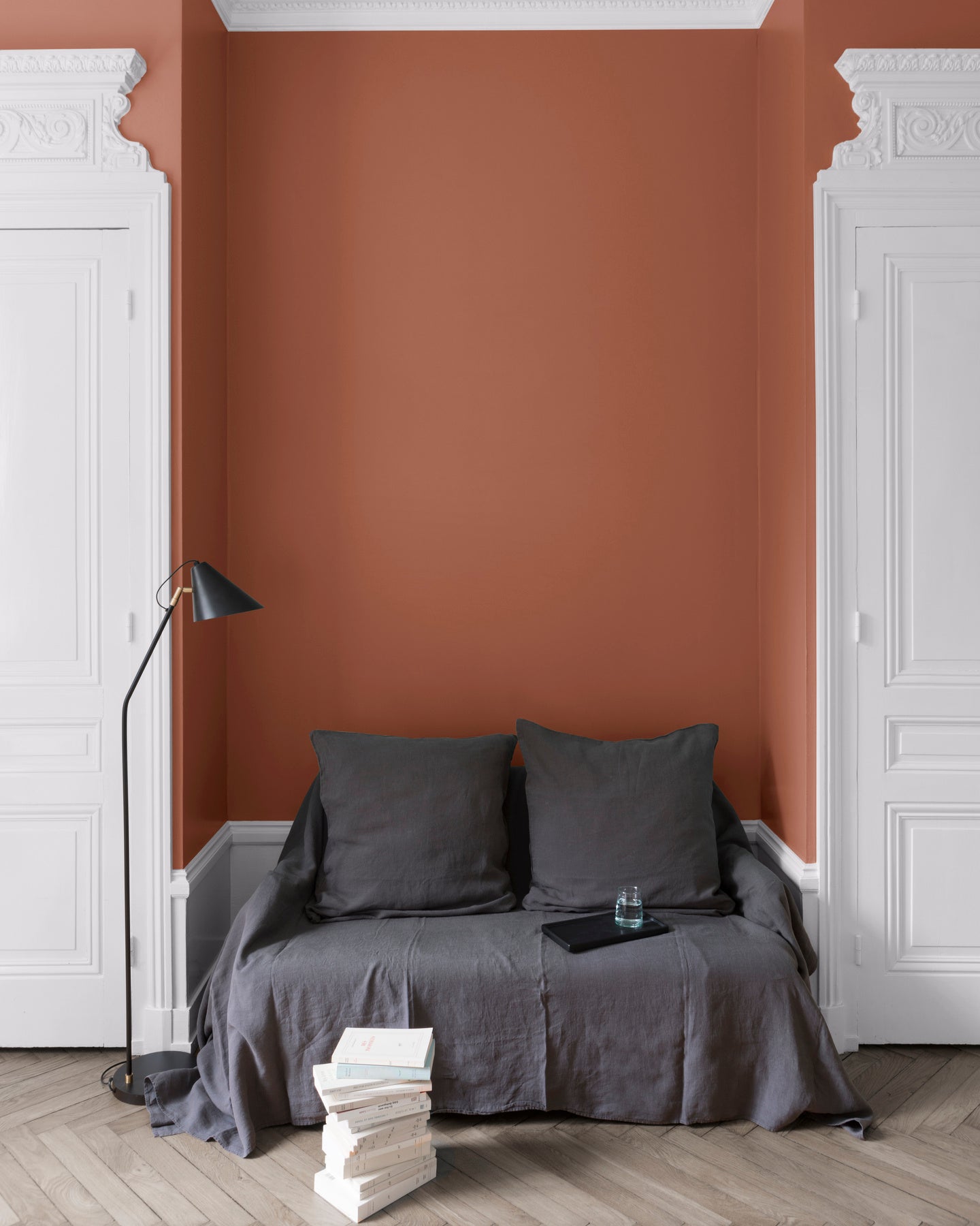 Salon aux murs Roux du Goupil, Velours de Peinture Libéron, avec canapé gris, portes blanches et parquet clair.