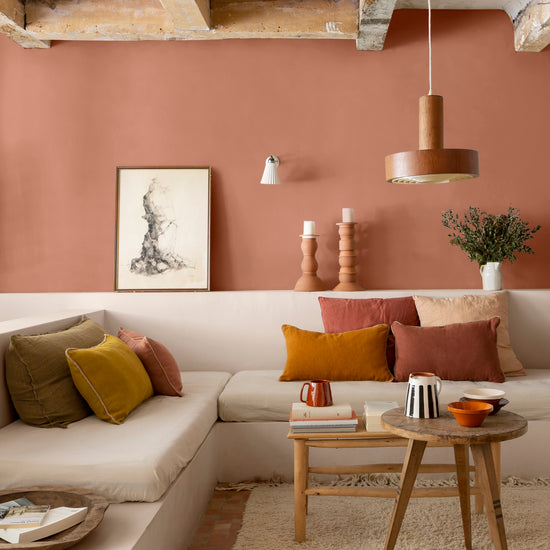 Salon aux murs terre cuite d’Anjou, Velours de Peinture Libéron, avec banquette maçonnée, coussins chauds et poutres en bois.
