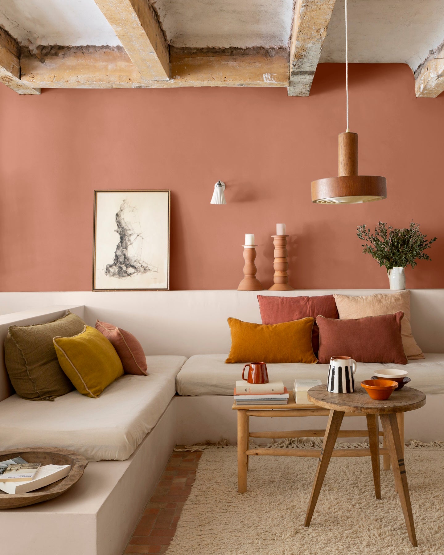 Salon aux murs terre cuite d’Anjou, Velours de Peinture Libéron, avec banquette maçonnée, coussins chauds et poutres en bois.