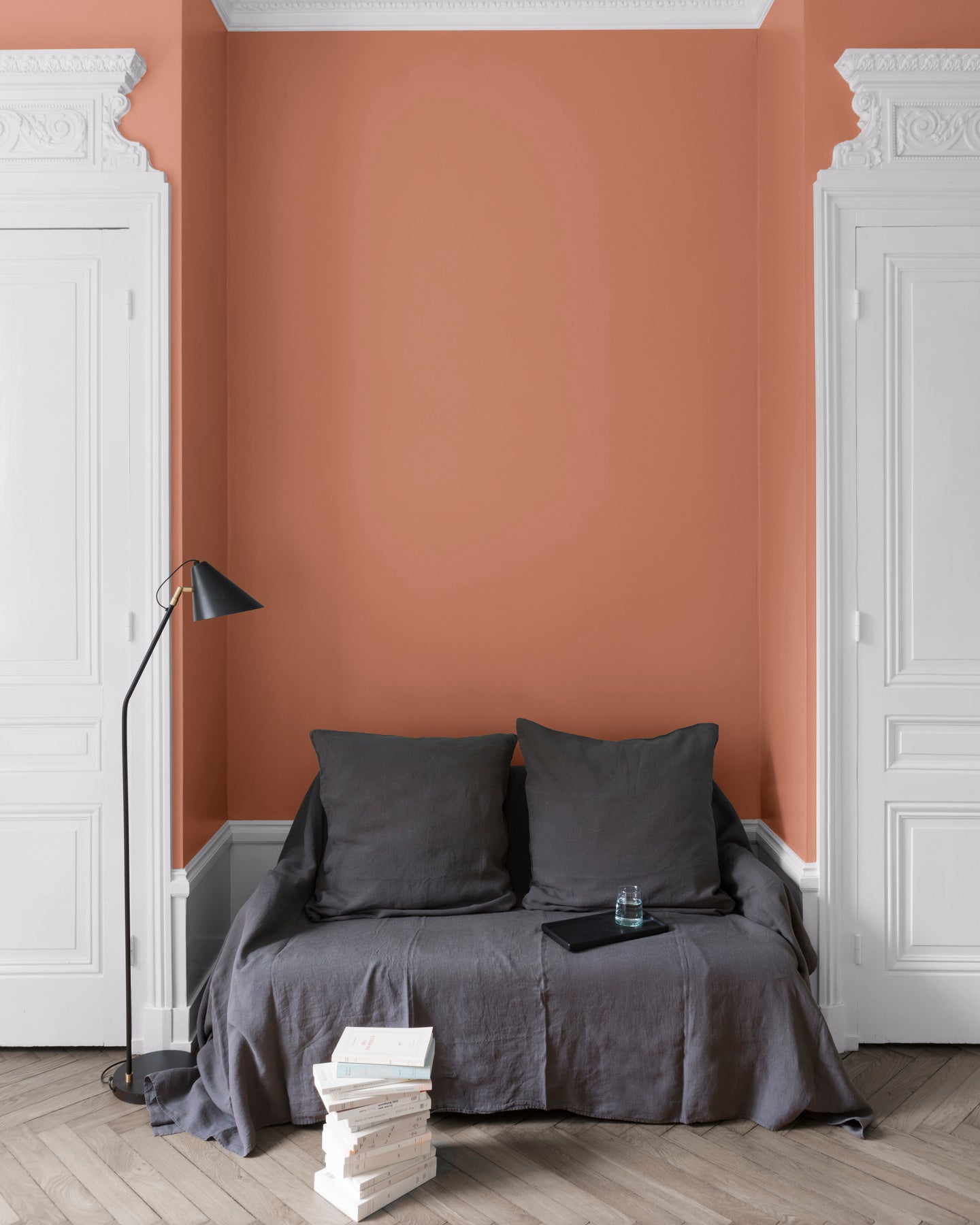 Salon aux murs Terre Cuite, Velours de Peinture Libéron, avec canapé gris, portes blanches et parquet clair.
