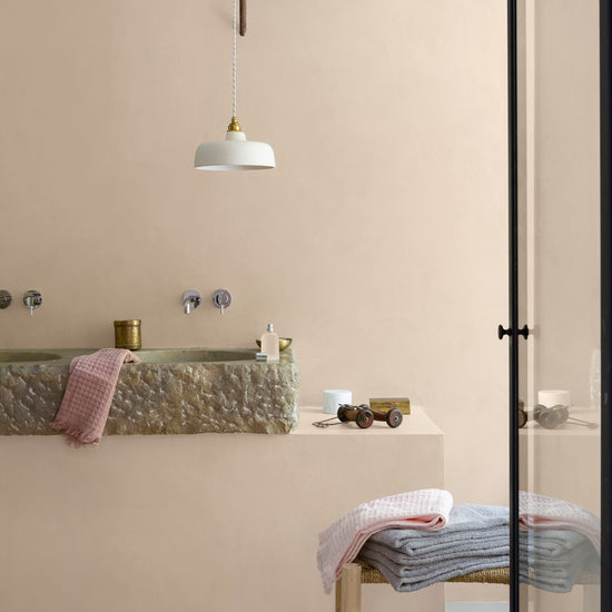 Salle de bain aux murs vélin, Velours de Peinture Libéron, avec vasque en pierre, suspension blanche et linge pastel.