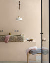 Salle de bain aux murs vélin Libéron, avec vasque en pierre, suspension blanche, serviettes pliées et ambiance douce.
