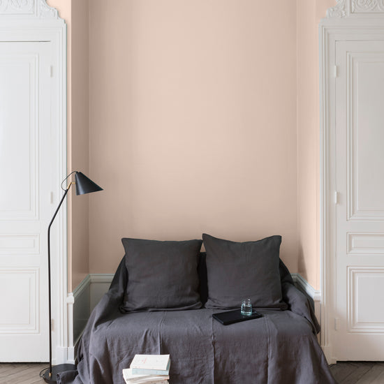 Salon aux murs vélin Libéron, avec canapé gris, portes blanches, lampadaire noir et parquet clair.