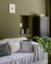 Salon aux murs vert bocage, Velours de Peinture Libéron, avec canapé blanc, coussins clairs et armoire noire.