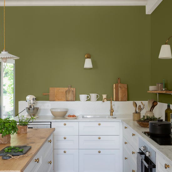 Cuisine lumineuse aux murs verts, peinture Velours de Peinture Vert Herbarium Libéron, avec îlot central en bois et meubles blancs