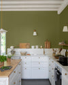 Cuisine lumineuse aux murs verts, peinture Velours de Peinture Vert Herbarium Libéron, avec îlot central en bois et meubles blancs