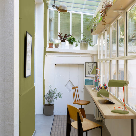 Bureau verrière aux murs vert herbarium, Velours de Peinture Libéron, avec plantes, plan de travail en bois et chaises.