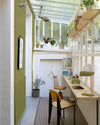 Bureau verrière aux murs vert herbarium, Velours de Peinture Libéron, avec plantes, plan de travail en bois et chaises.