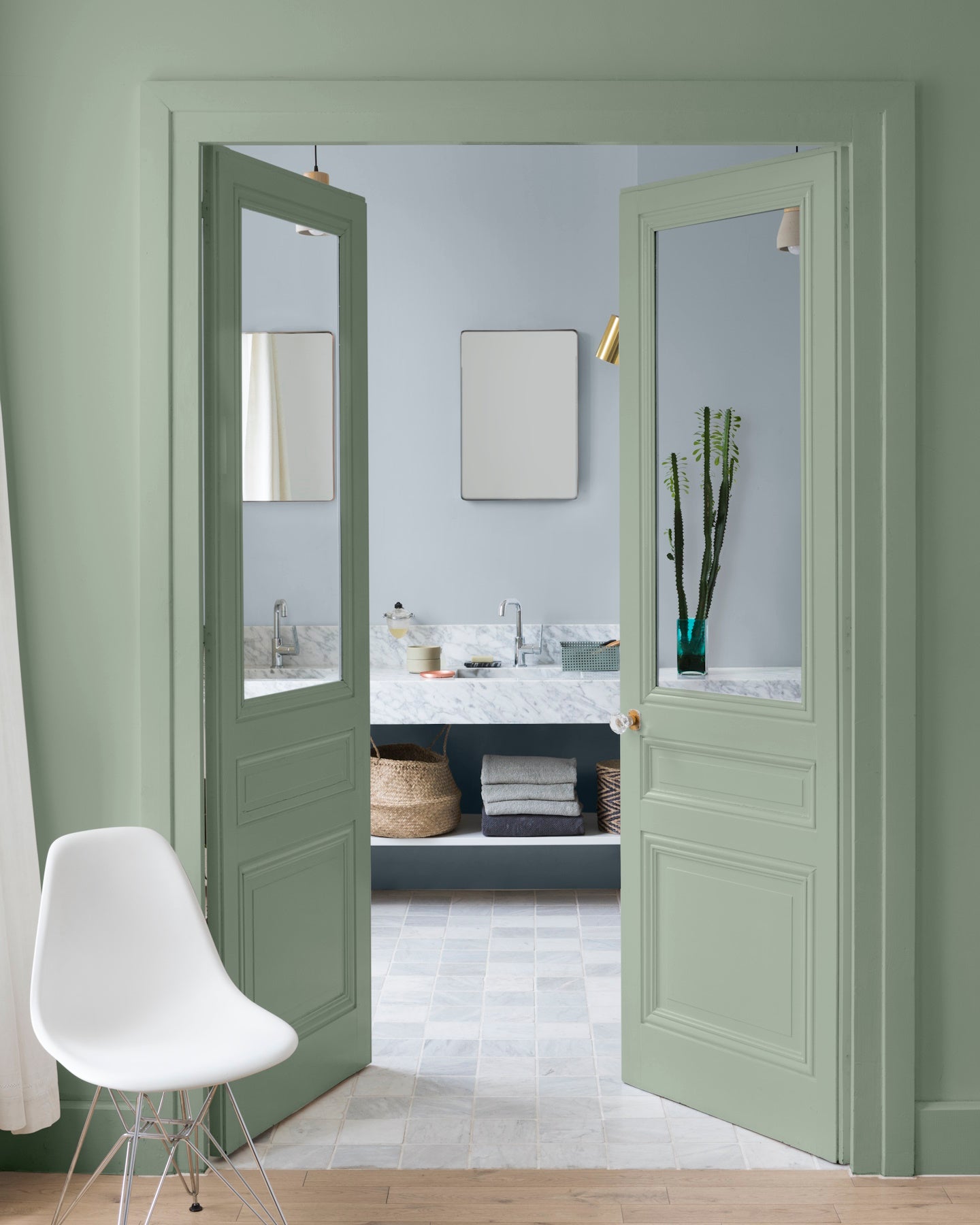 Salle de bain aux murs vert Luxembourg et petit bleu Libéron, avec portes vitrées vertes, chaise blanche et meuble vasque.