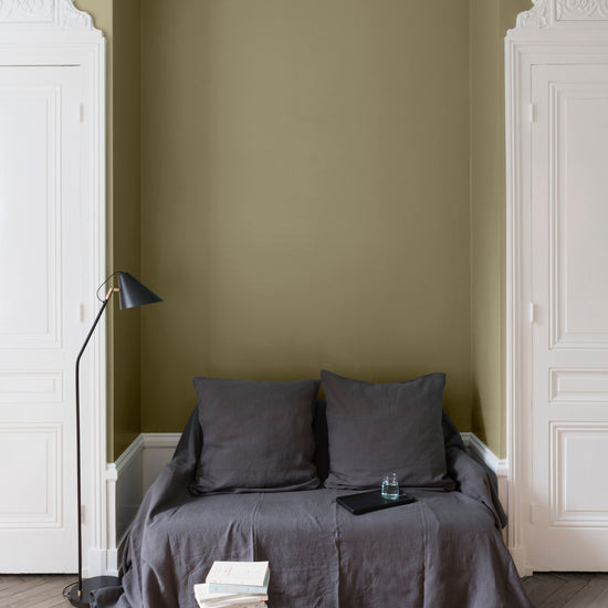 Salon aux murs Vert Picholine Libéron, avec canapé gris, portes blanches, lampadaire noir et parquet clair.