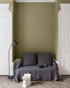 Salon aux murs Vert Picholine Libéron, avec canapé gris, portes blanches, lampadaire noir et parquet clair.