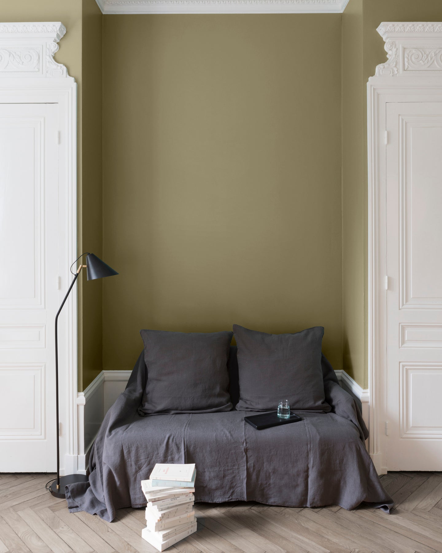 Salon aux murs Vert Picholine Libéron, avec canapé gris, portes blanches, lampadaire noir et parquet clair.