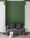 Salon aux murs vert potager Libéron, avec canapé gris, portes blanches, lampadaire noir et parquet clair.