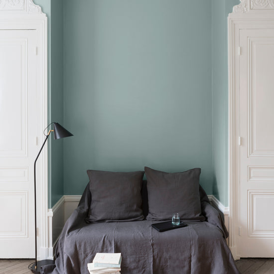 Salon aux murs Vert Rocaille, Velours de Peinture Libéron, avec canapé gris, portes blanches et parquet clair.
