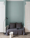 Salon aux murs Vert Rocaille, Velours de Peinture Libéron, avec canapé gris, portes blanches et parquet clair.