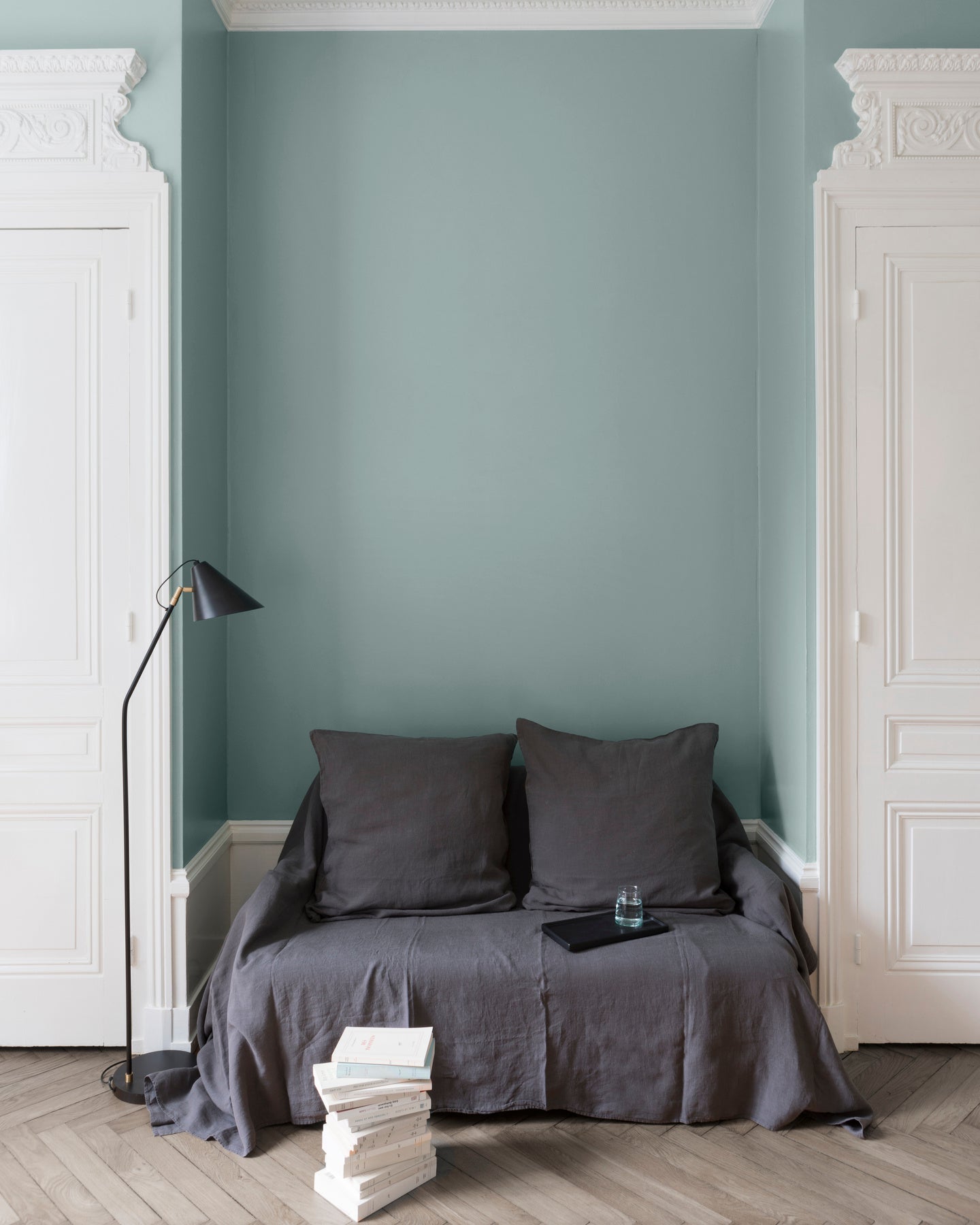 Salon aux murs Vert Rocaille, Velours de Peinture Libéron, avec canapé gris, portes blanches et parquet clair.