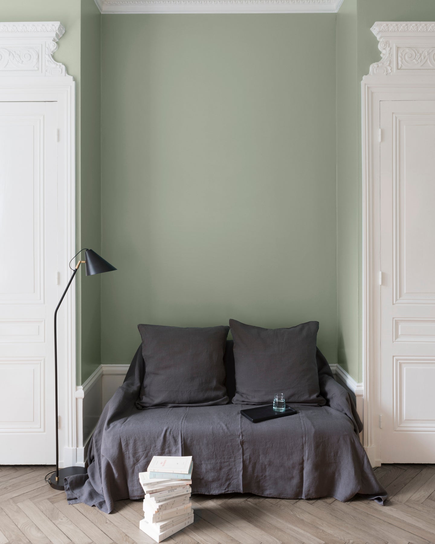Salon aux murs Vert Sauge, Velours de Peinture Libéron, avec canapé gris, portes blanches et parquet clair.