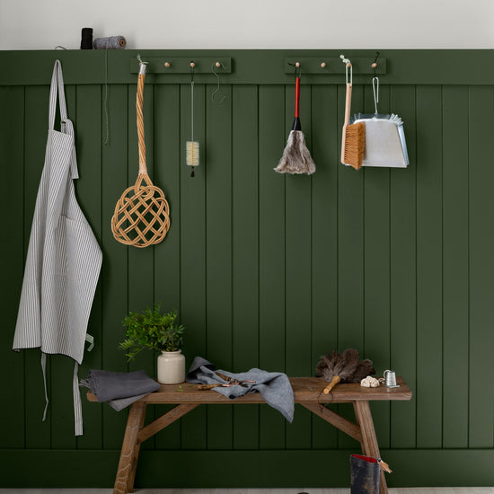Entrée aux murs vert treillis et blanc grisaille, Velours de Peinture Libéron, avec patères, banc en bois et bottes.