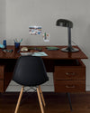 Coin bureau verni avec le Vernis Bistrot Chêne Foncé Libéron, chaise et lampe noires, photos accrochées sur le mur gris.