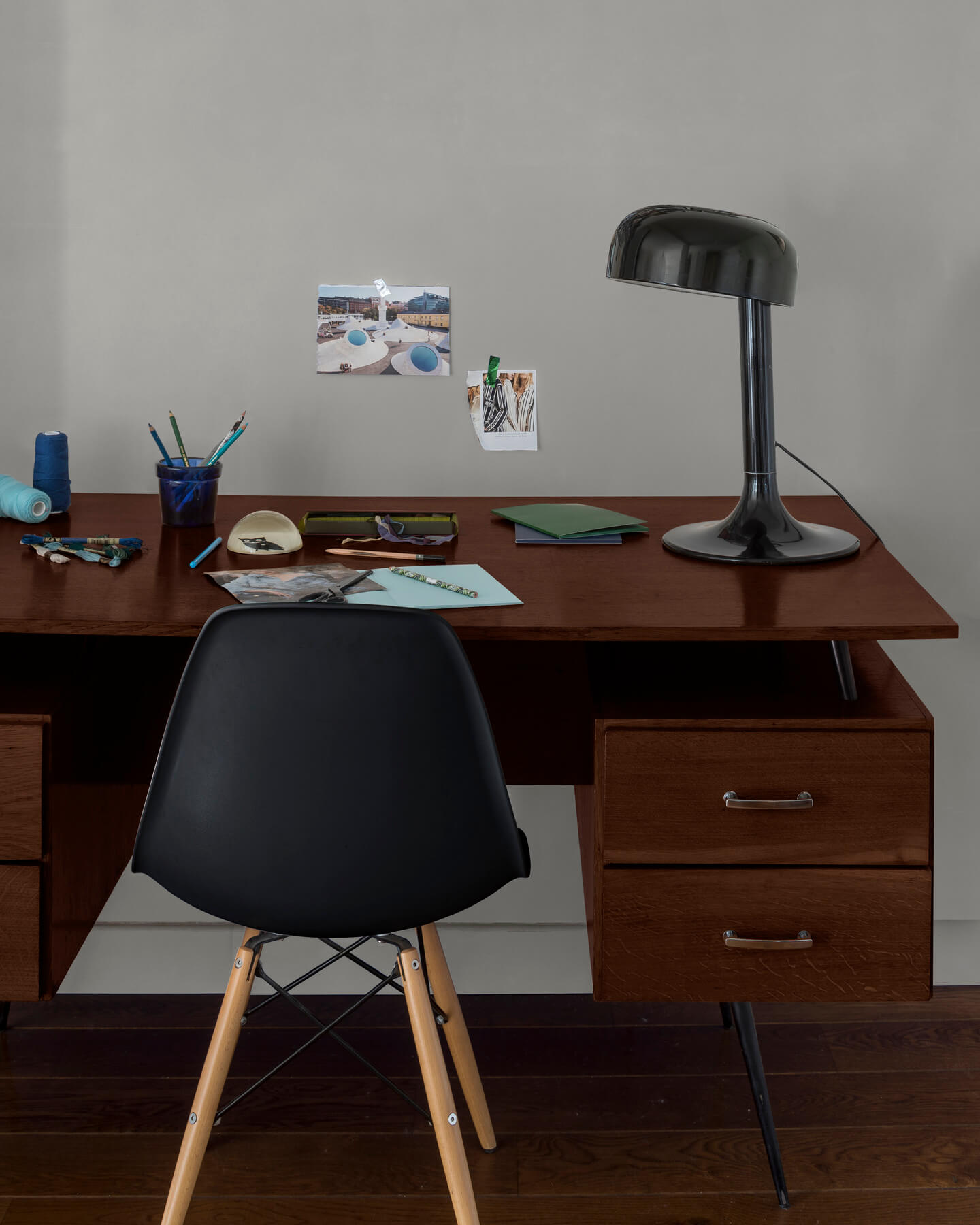 Coin bureau verni avec le Vernis Bistrot Chêne Foncé Libéron, chaise et lampe noires, photos accrochées sur le mur gris.