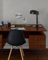 Coin bureau verni avec le Vernis Bistrot Chêne Moyen Libéron, chaise et lampe noires, photos accrochées sur le mur gris.