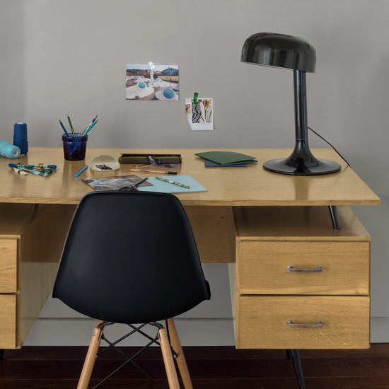 Coin bureau verni avec le Vernis Bistrot Incolore Libéron, chaise et lampe noires, photos accrochées sur le mur gris.
