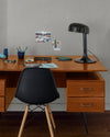 Coin bureau verni avec le Vernis Bistrot Merisier Libéron, chaise et lampe noires, photos accrochées sur le mur gris.